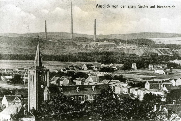 Mechernich mit der im Zweiten Weltkrieg zerbombten Pfarrkirche und den Schornsteinen der Bleihütte im Hintergrund.